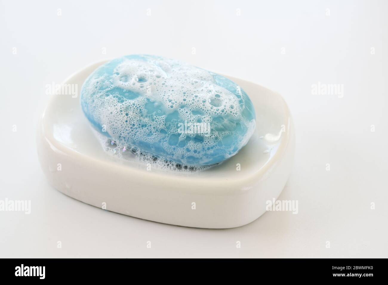 barra di sapone blu con laccio e bolle su una capsula di sapone bianco, salute e concetto di igiene contro infezione da virus, spazio di copia, fuoco selezionato Foto Stock