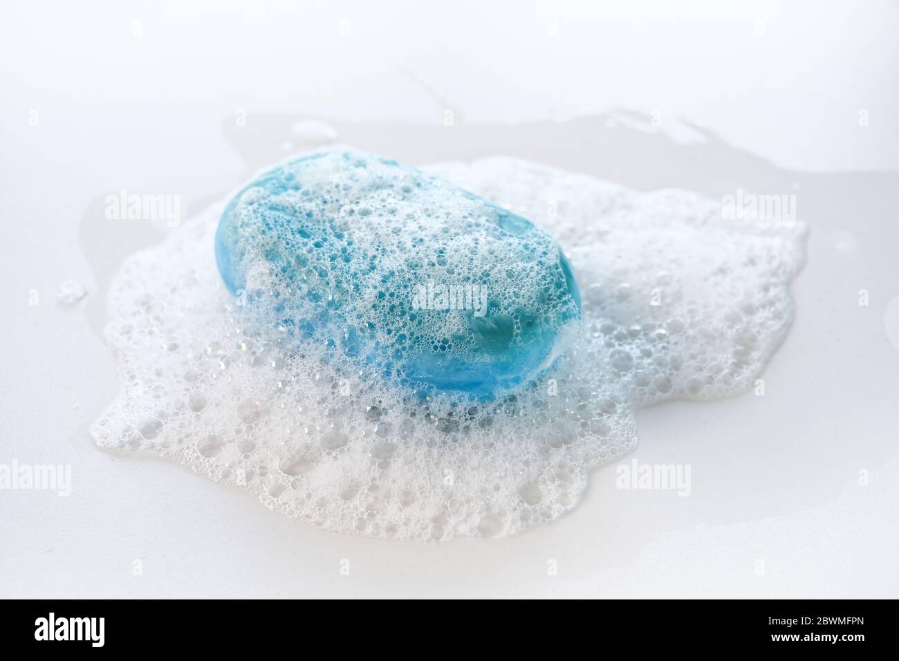 bar di sapone blu con un sacco di schiuma e bolle su uno sfondo bianco, salute e concetto di igiene contro l'infezione da coronavirus, copia spazio, sele Foto Stock