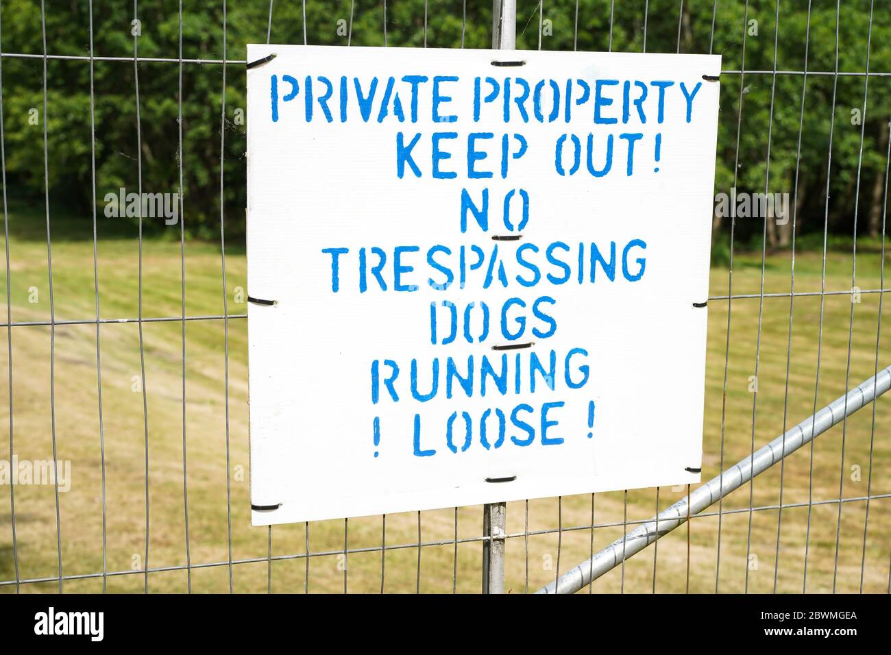 Tenere fuori il cartello della proprietà privata. Cartello pubblico di avviso di non trasgressione, cani che corrono sciolti, campagna del Regno Unito. Foto Stock