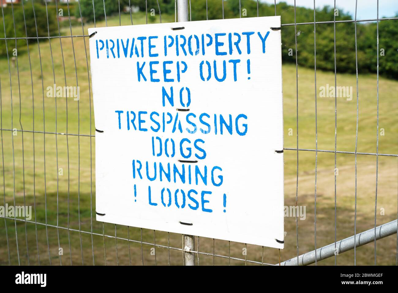 Tenere fuori il cartello della proprietà privata. Cartello pubblico di avviso di non trasgressione, cani che corrono sciolti, campagna del Regno Unito. Foto Stock