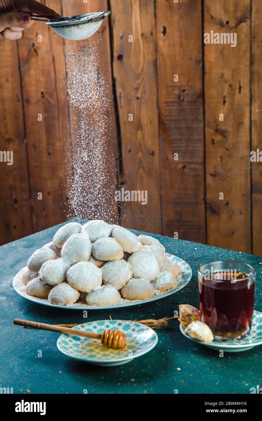Femmina mano spruzzando zucchero in polvere sui biscotti Foto Stock