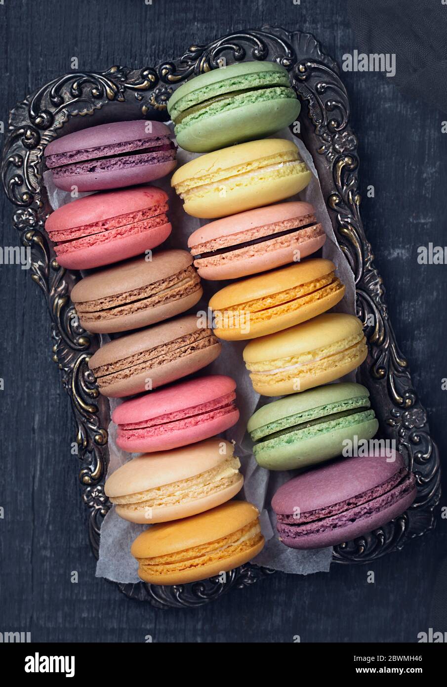 Macaron colorati al buio su un sfondo di legno Foto Stock