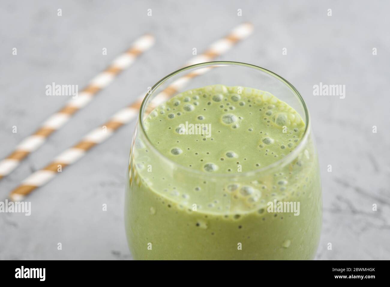 Frullato verde con spinaci e avocado in vetro su sfondo grigio Foto Stock