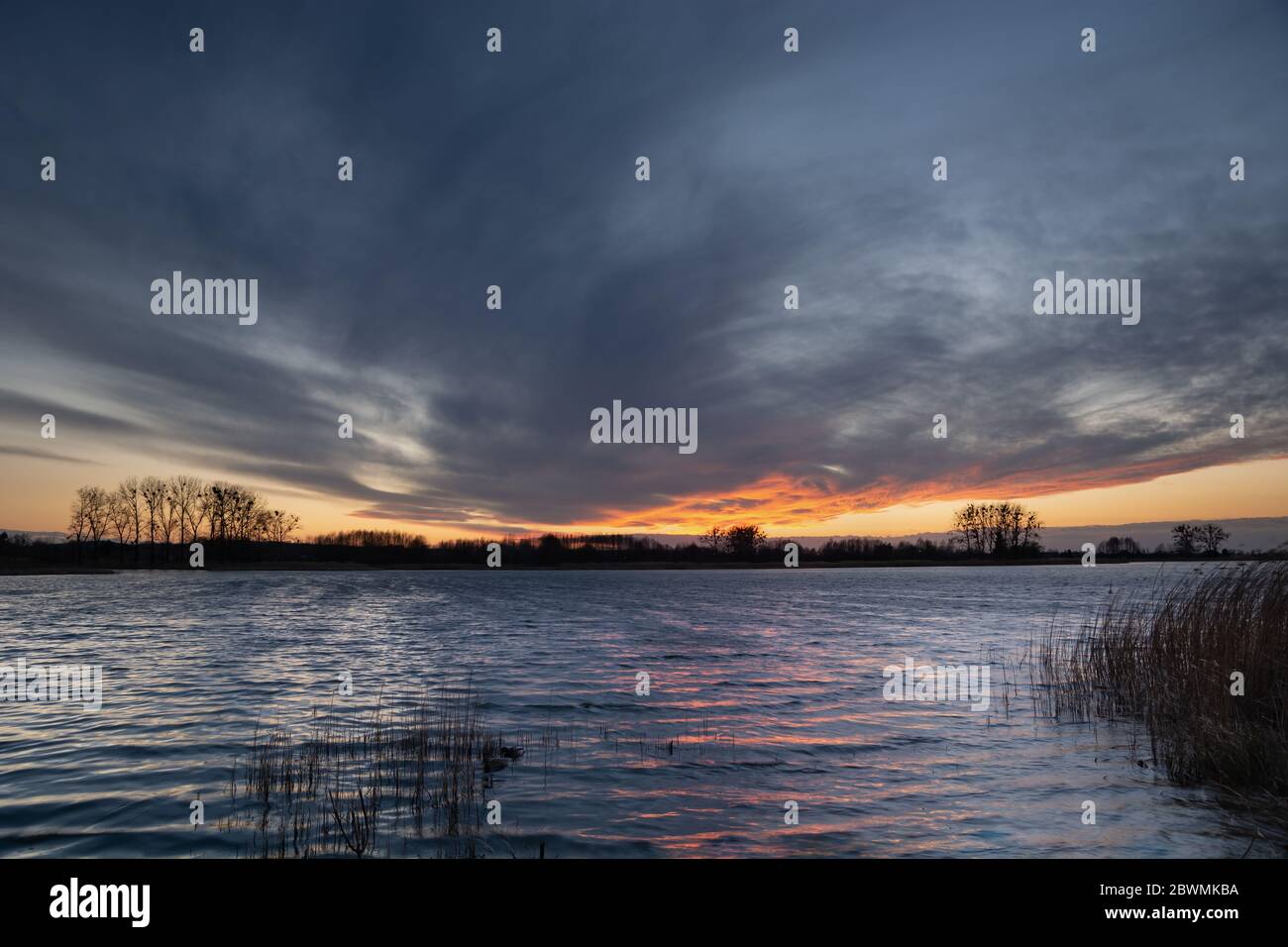 Fantastiche nuvole sul cielo dopo il tramonto su un lago calmo con canne Foto Stock