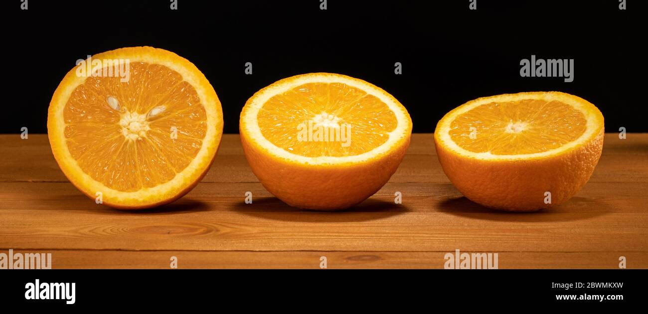 arance su un tavolo di legno, arance tritate, tre metà di arance Foto Stock