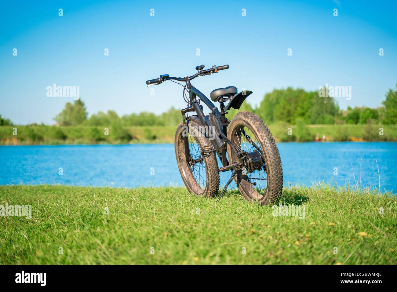 Bicicletta elettrica con ruote spesse vicino al lago. Un piacevole hobby sportivo che ti permette di viaggiare. Moto da fatbike. Foto Stock