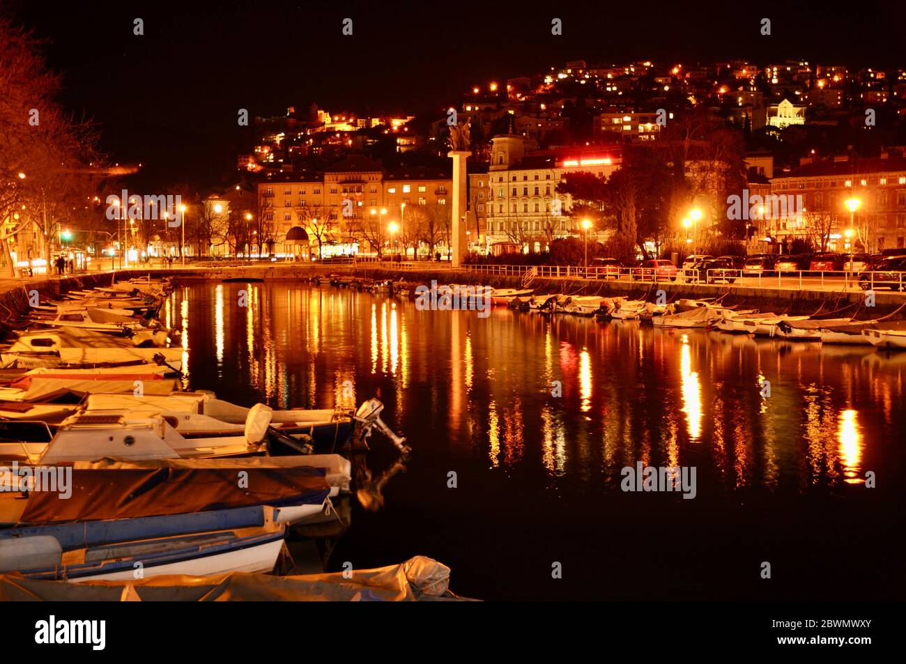 Canale del fiume con paesaggi urbani notturni con chiatte ormeggiate. Rijeka città luci notturne in Croazia. Foto Stock