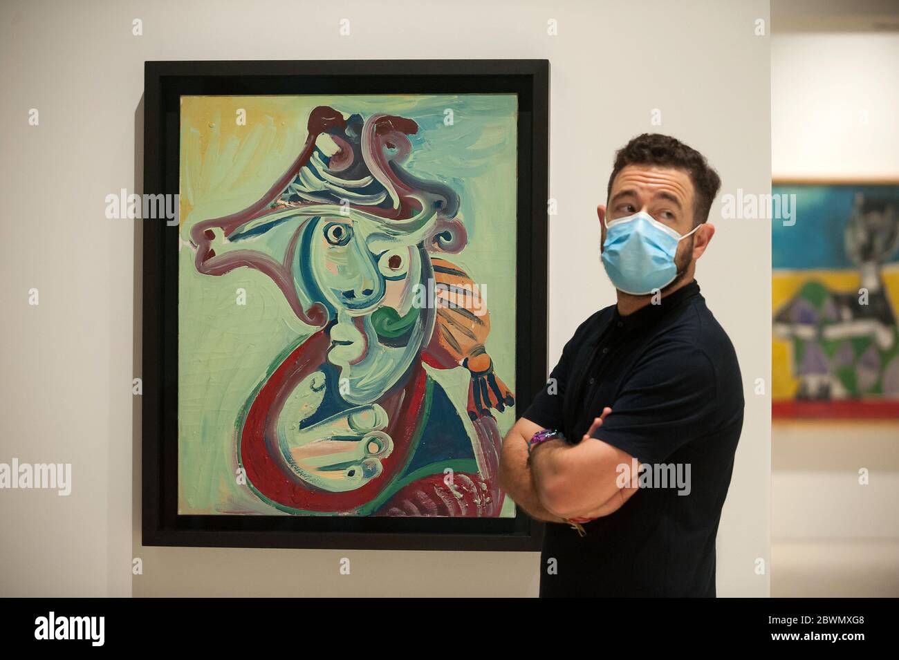 Un dipendente che indossa una maschera si trova accanto ad un dipinto che  viene esposto durante la mostra "Dialogues with Picasso: Collection  2020-2023" al Museo Picasso. La nuova collezione permanente arriva al