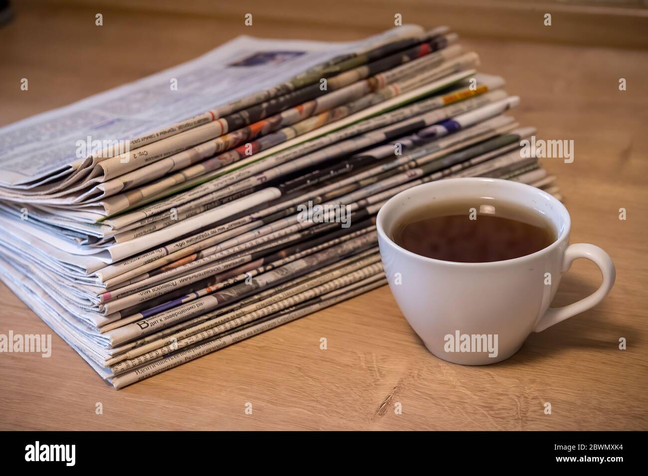 fuoco selettivo della tazza di tè che impilano i giornali piegati posizionare su un tavolo di legno Foto Stock