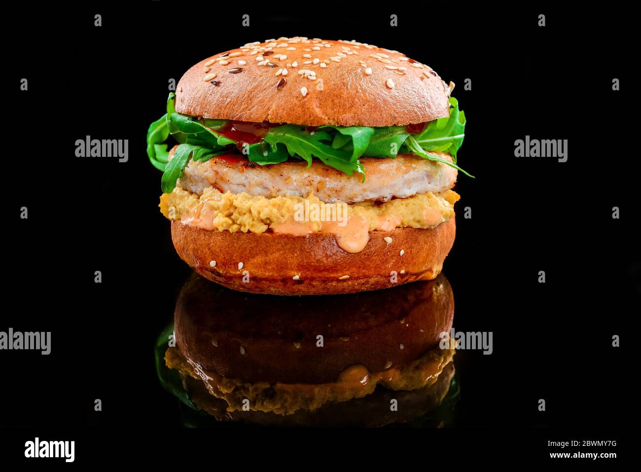 Hamburger di pollo con salsa al formaggio su sfondo nero Foto Stock