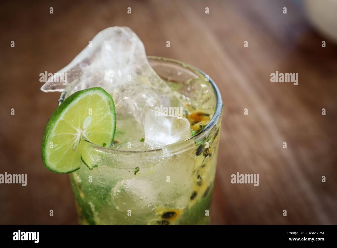 Cocktail di mojito alla frutta con cannuccia metallica su tavolo di legno nella caffetteria Foto Stock