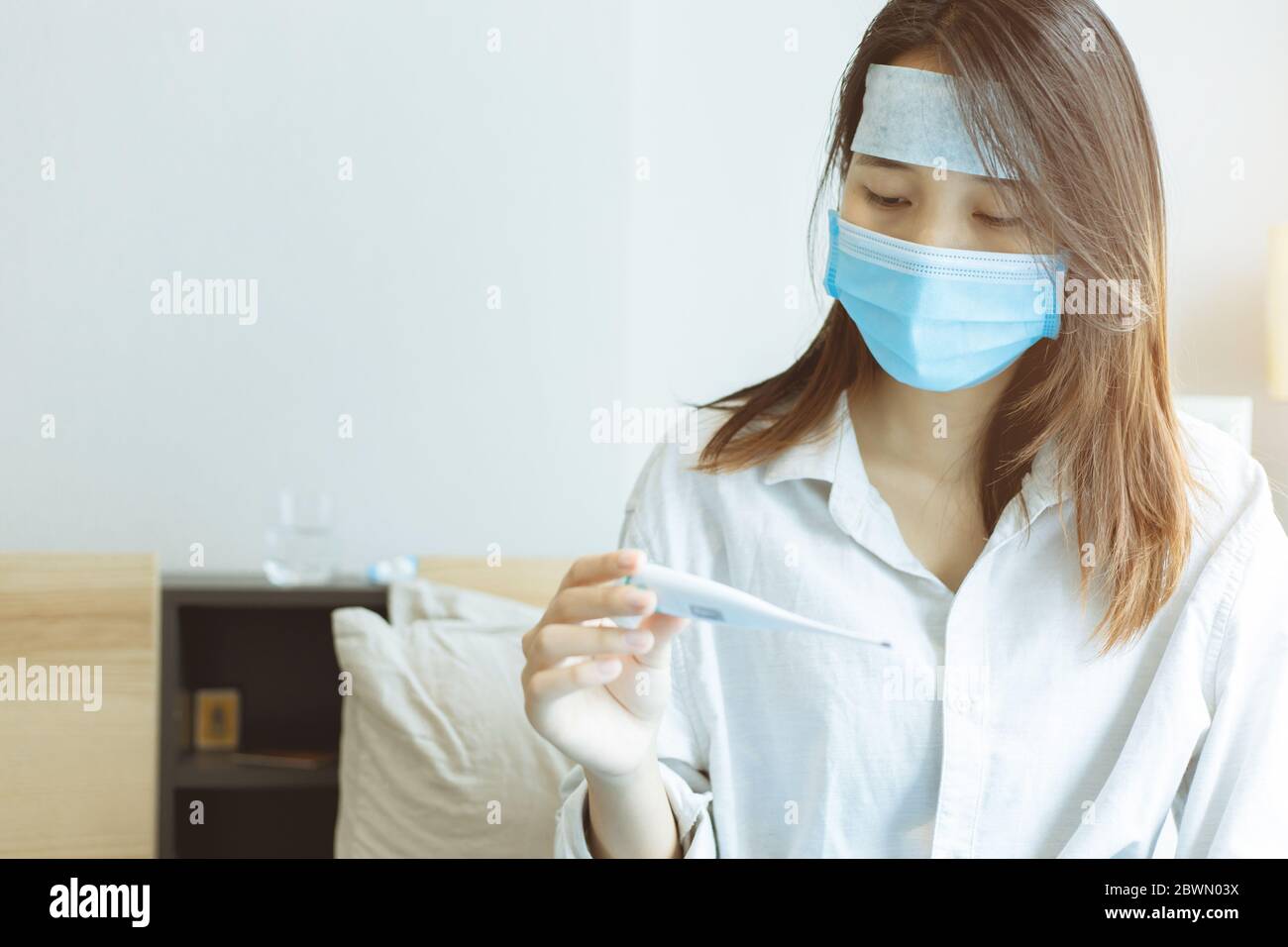 Asian teen Coronavirus influenza infettato guardando termometro digitale ansiosamente che sarebbe infettato con il virus Covid-19 Foto Stock