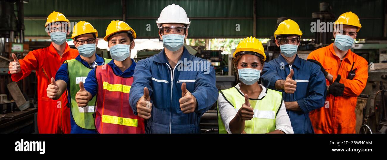 Gruppo di lavoratori che indossano la visiera protettiva o la maschera facciale monouso lavorano in fabbrica per aiutare a prevenire e combattere il Coronavirus (Covid-19) o l'inquinamento da polveri dell'aria Foto Stock