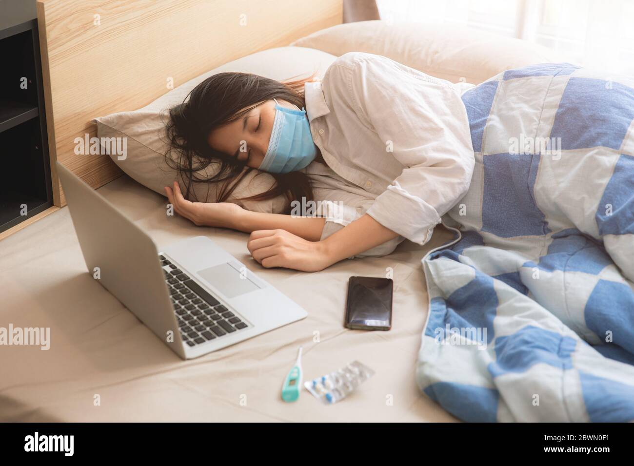 Ragazza asiatica teen malattia malata giaceva sul letto indossando maschera con computer portatile. Foto Stock