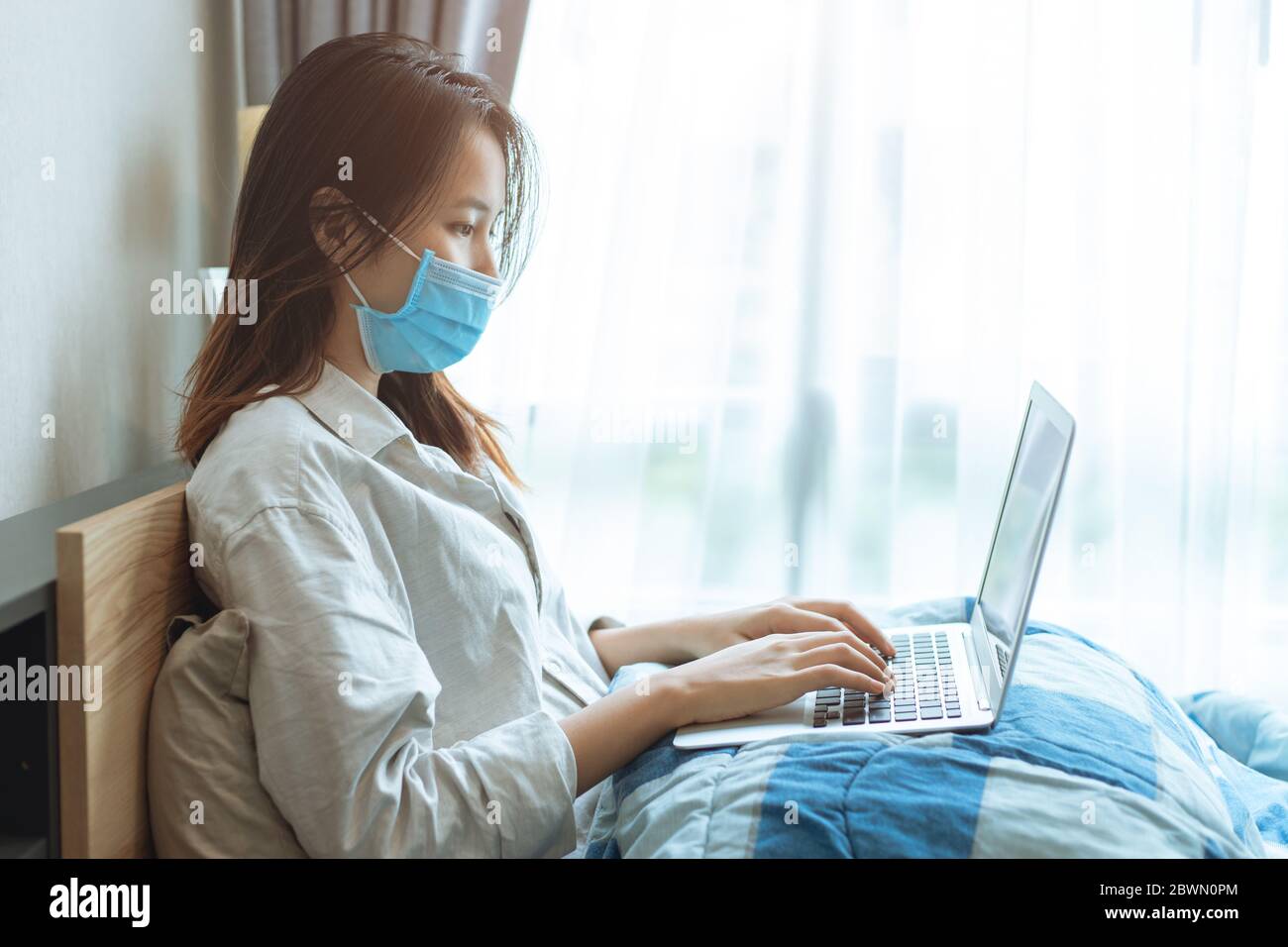 Persone Asian ragazza teen Coronavirus influenza infettato lavorando a casa da computer portatile online indossare maschera di protezione per la disposizione viso prevenire Covid-19 spalmare Foto Stock
