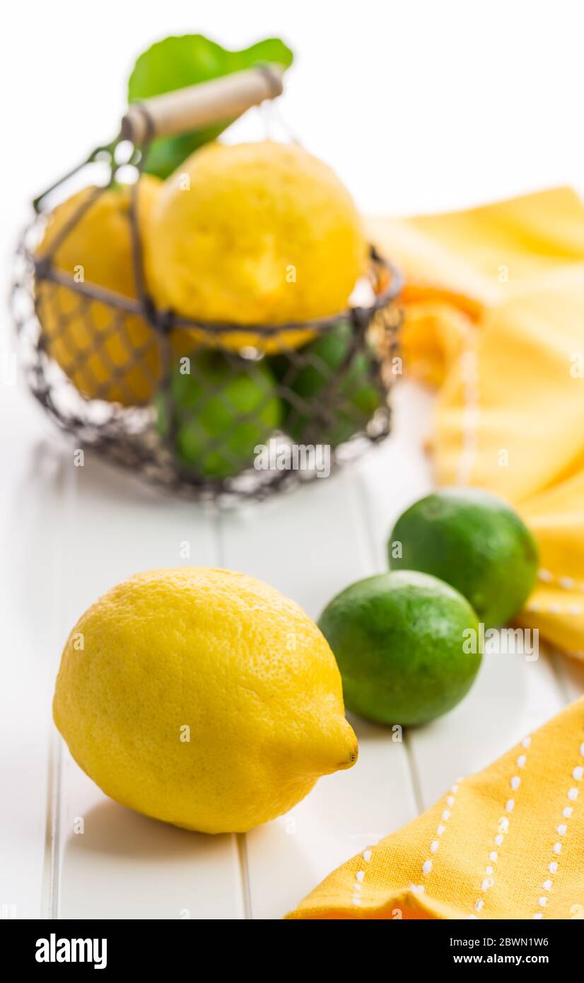 Limoni e lime organici in un cesto su sfondo bianco Foto Stock
