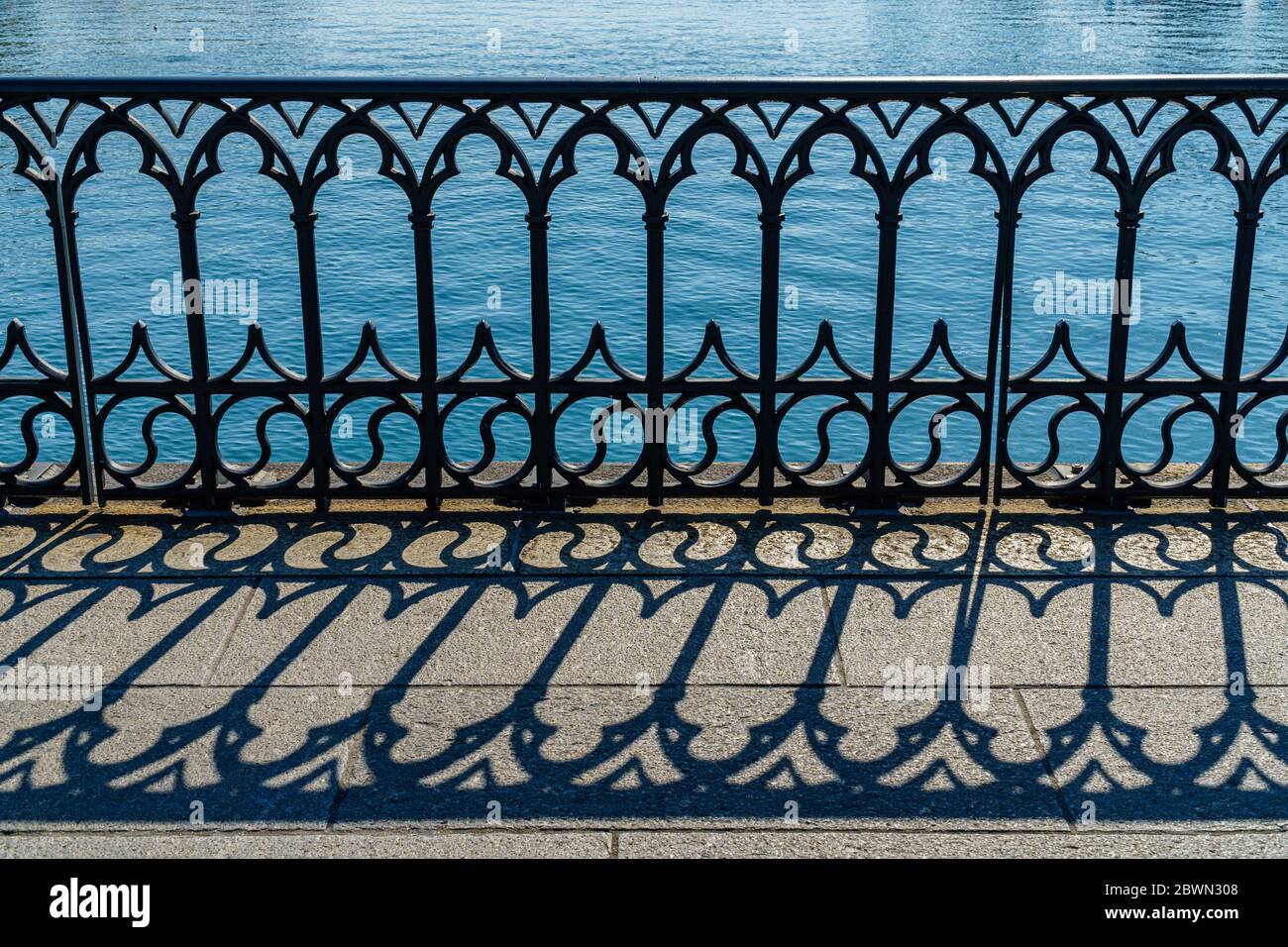 Primo piano della balaustra della Münsterbrücke Svizzera che forma un disegno interessante con la sua ombra sul terreno Foto Stock