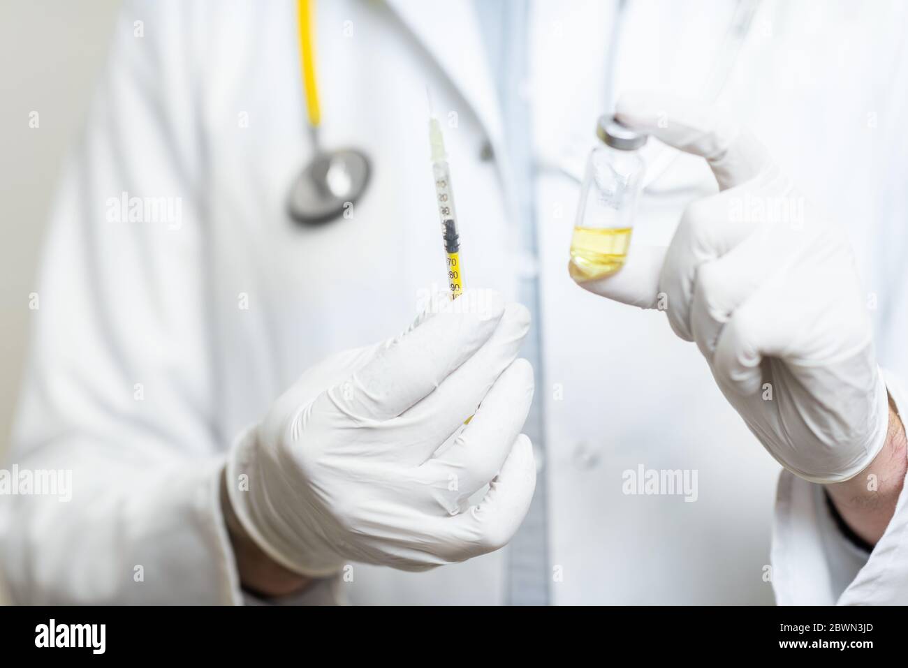 Medico che tiene la siringa con alcuni farmaci o vaccini, vista ravvicinata messa a fuoco sulle mani in guanti medici Foto Stock