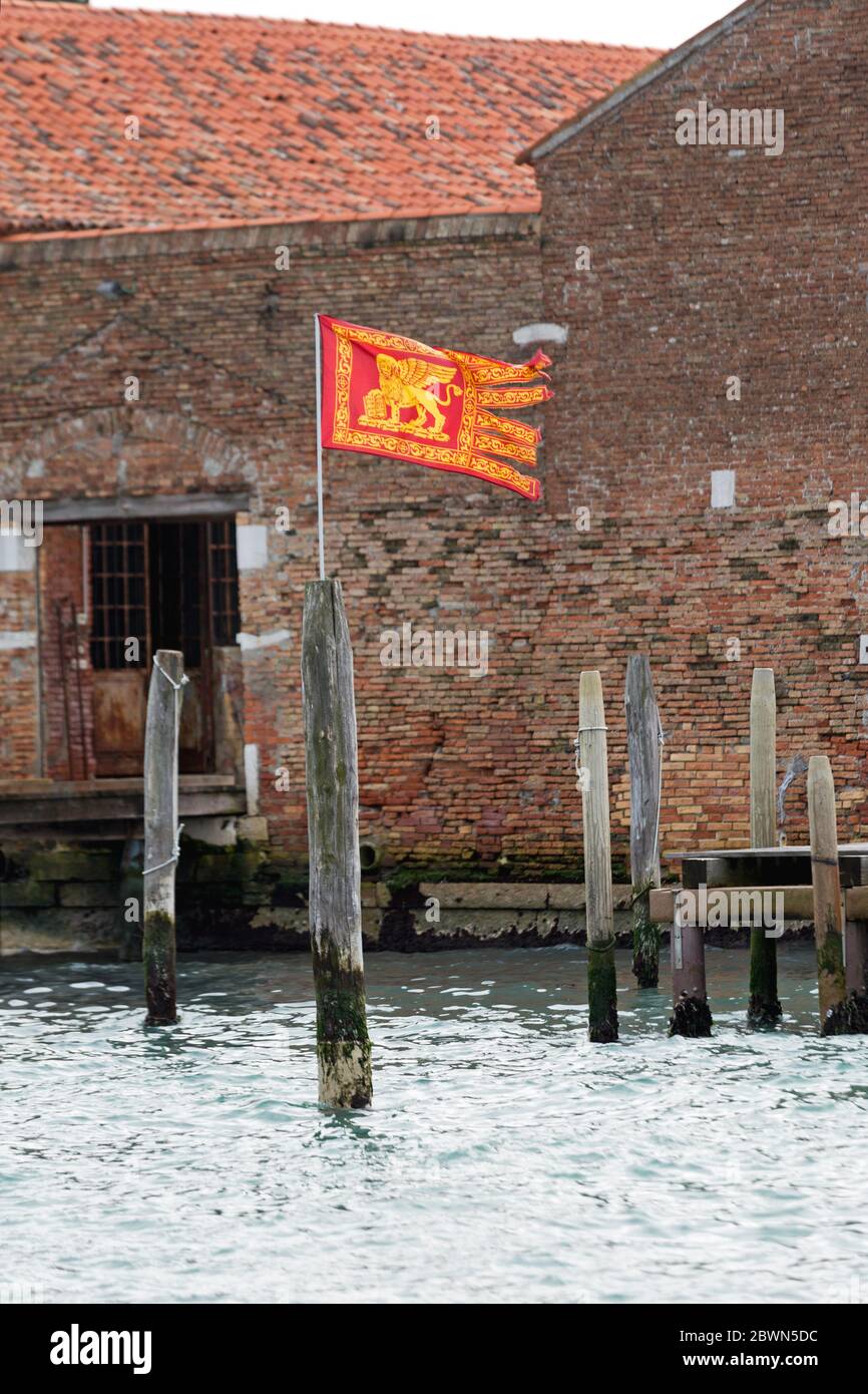 Bandiera della città di Venezia al Polo di legno nel canale Foto Stock