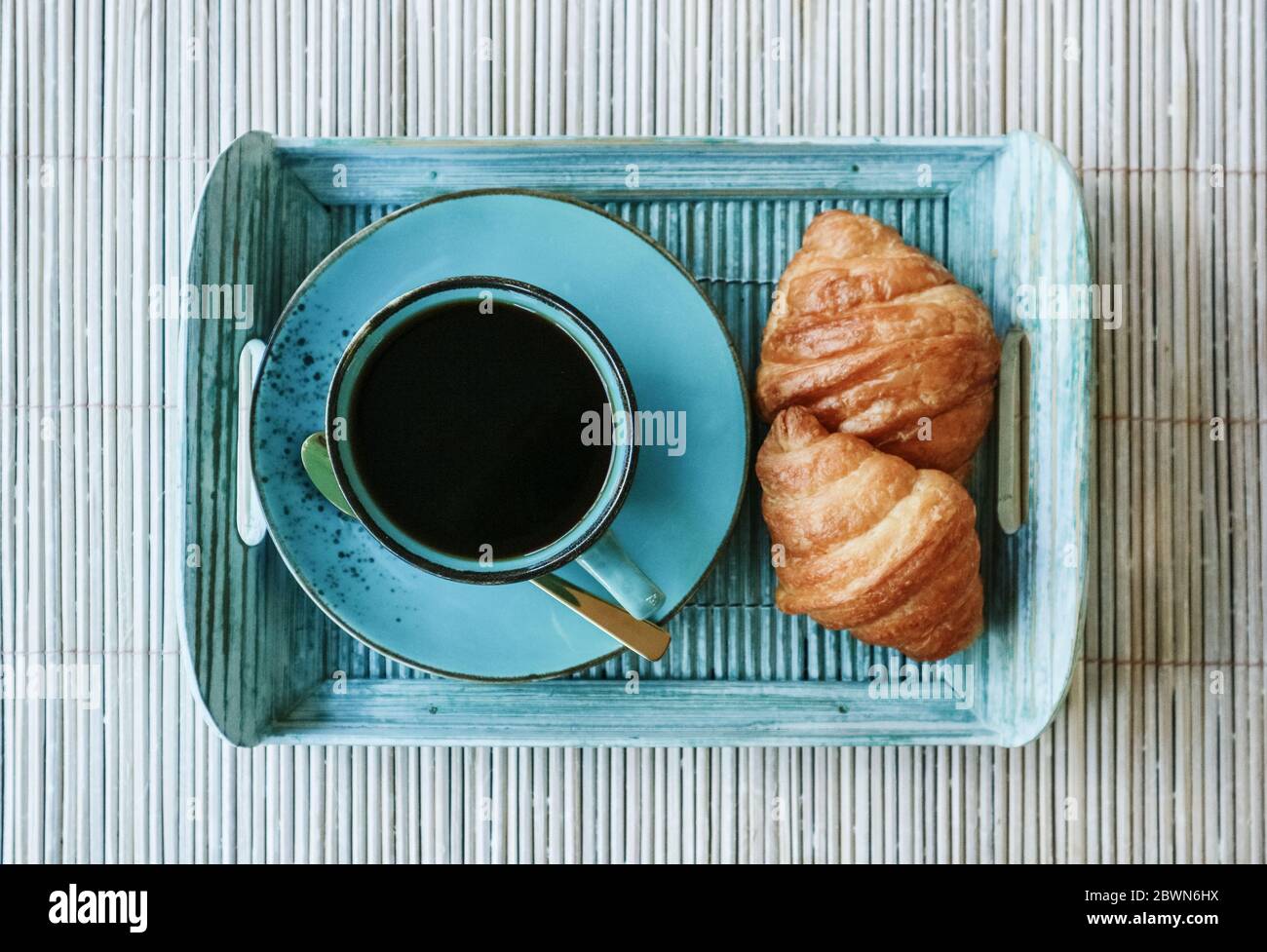 Tazza di caffè con croissant su vassoio di bambù blu all'aperto, vista dall'alto Foto Stock