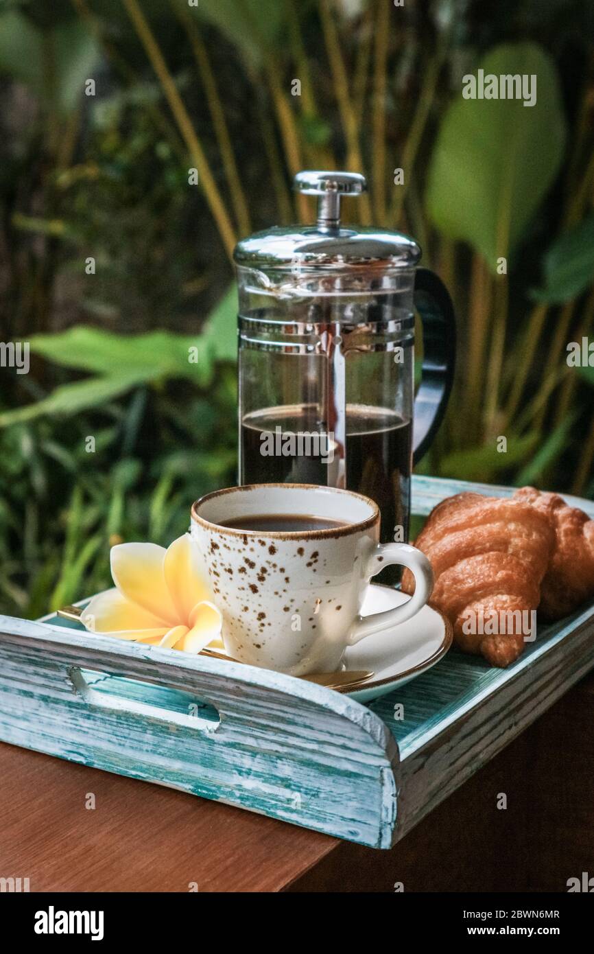 Tazza di caffè con croissant su vassoio di bambù blu all'aperto, guardaroba Foto Stock