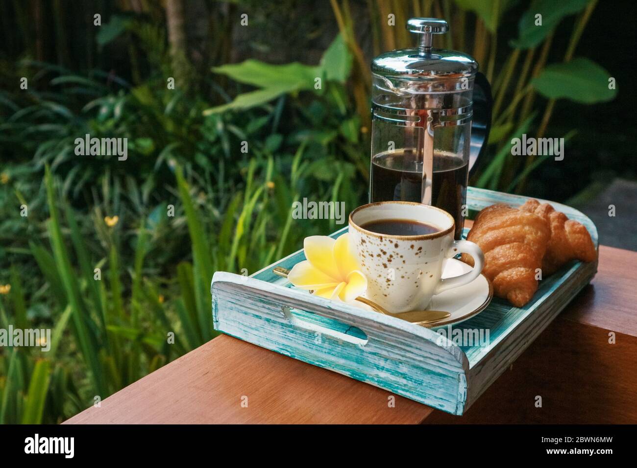 Tazza di caffè con croissant su vassoio di bambù blu all'aperto, guardaroba Foto Stock