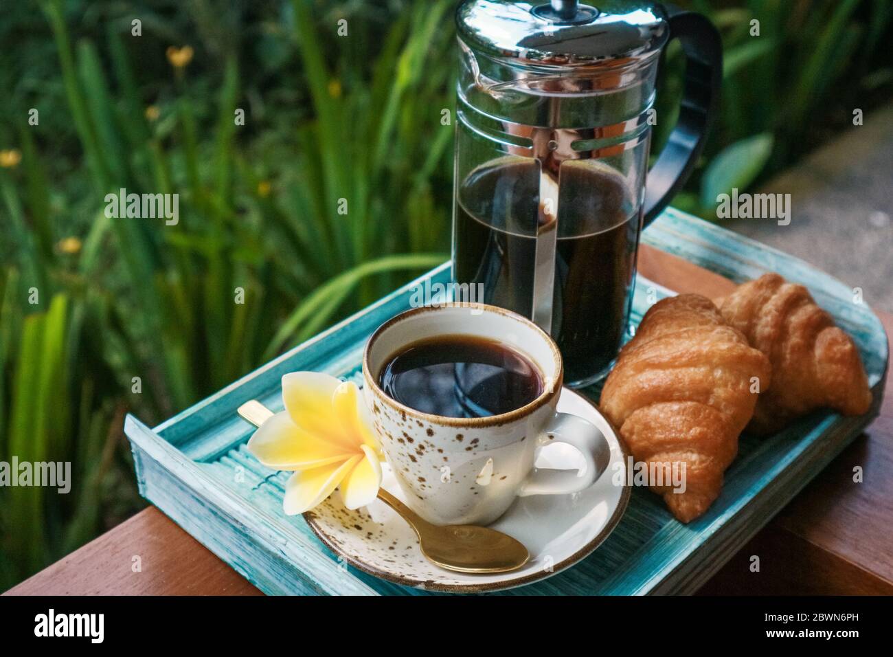 Tazza di caffè con croissant su vassoio di bambù blu all'aperto, guardaroba Foto Stock