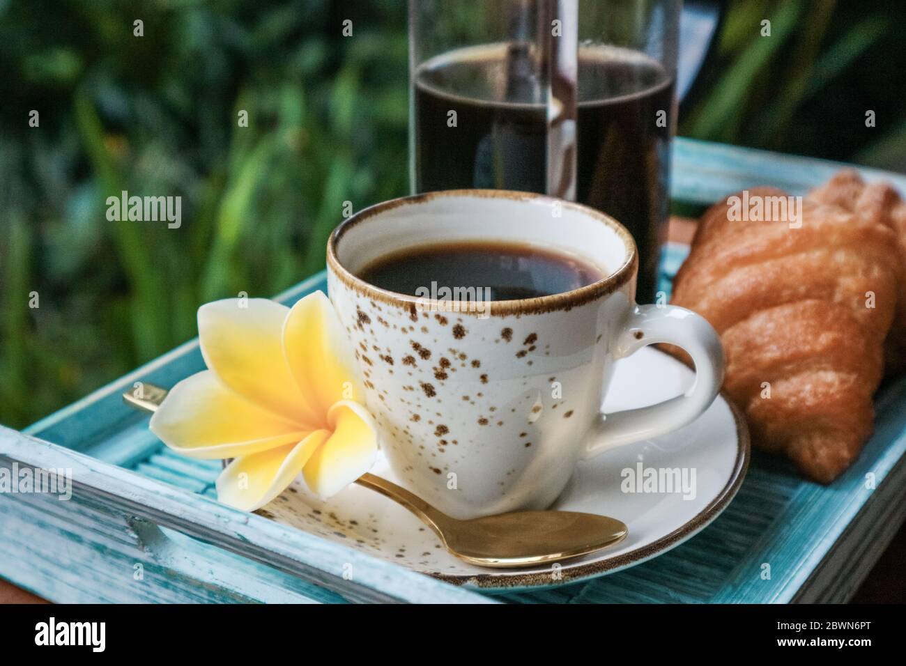 Tazza di caffè con croissant su vassoio di bambù blu all'aperto, guardaroba Foto Stock
