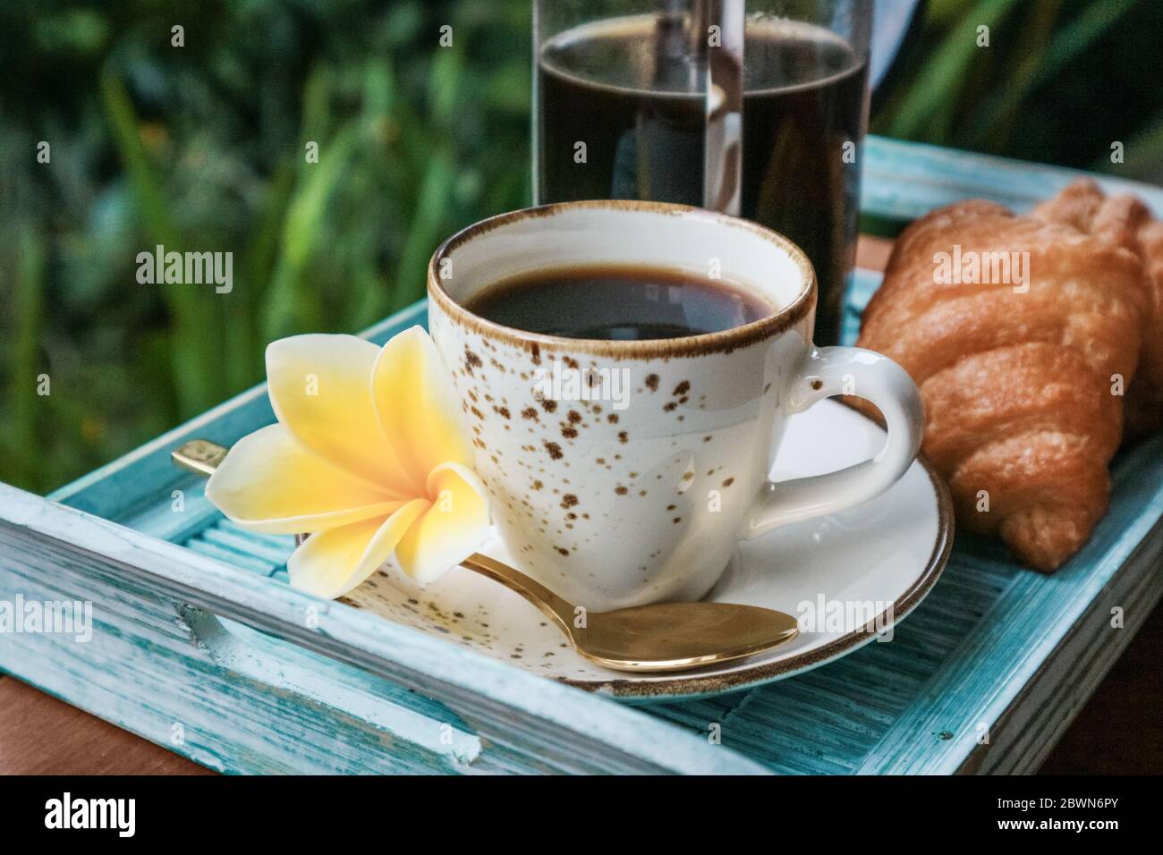 Tazza di caffè con croissant su vassoio di bambù blu all'aperto, guardaroba Foto Stock