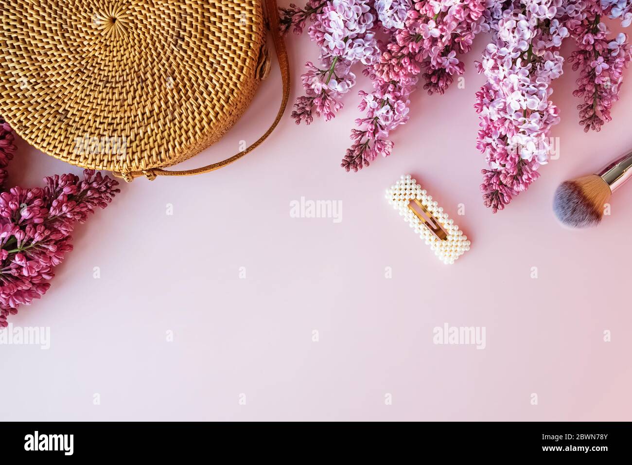 Sacco di paglia e fiori lilla su sfondo rosa con spazio per la copia Foto Stock
