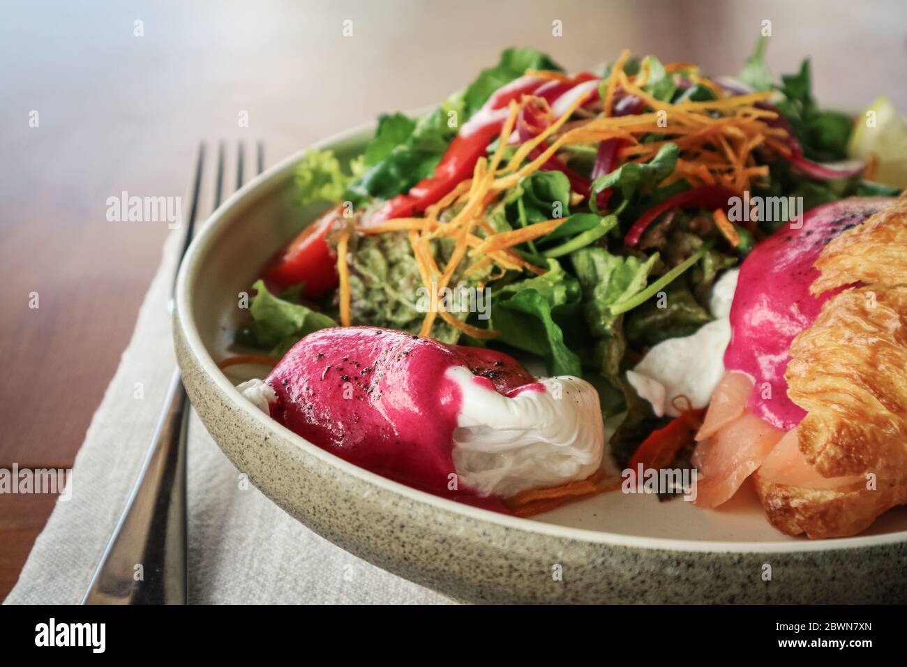 Salmone affumicato, patate brune di patate, pomodori ciliegini semi-secchi, salsa di barbabietole, uova in camicia, croissant al burro caldo, erba cipollina, erbe miste, pistach di schiacciamento Foto Stock