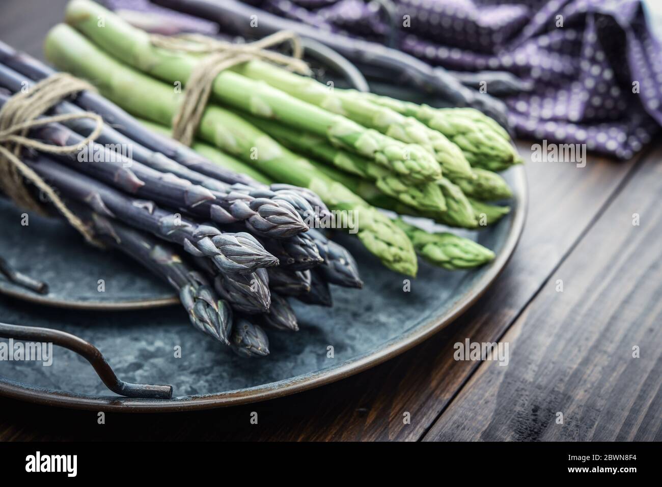 Un gambi commestibili e grezzi di asparagi su un vassoio su un chioseup di legno di fondo Foto Stock