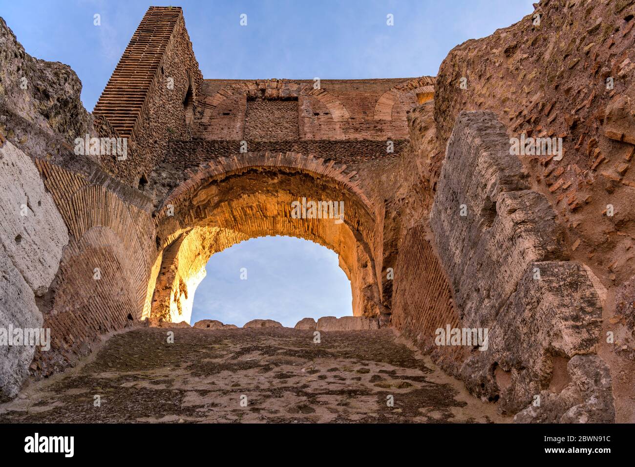 Arco di pietra - la luce del sole serale splende su un arco di pietra in cima all'antica parete alta del Colosseo. Roma, Italia. Foto Stock