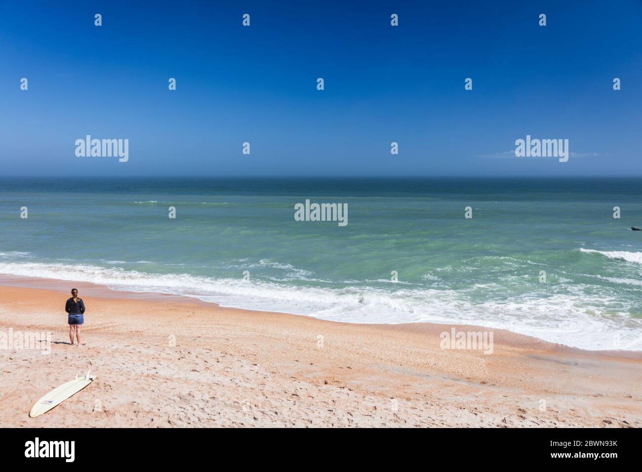 Donna stand alone sulla spiaggia vuota della Florida con surf Foto Stock