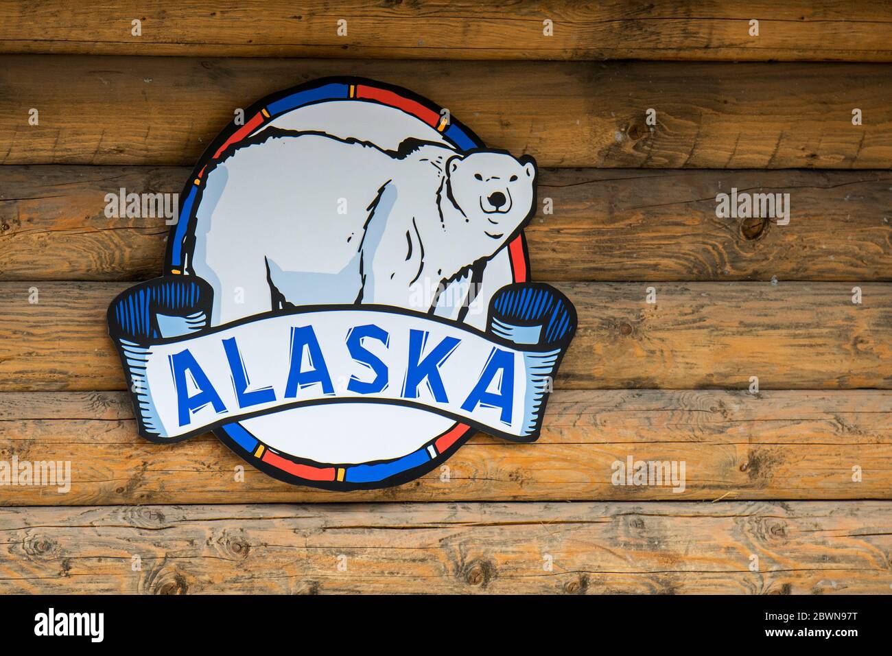 Alaska / Alaska emblema / insegne con simbolo di orso polare appeso su parete di legno di capanna di tronchi Foto Stock