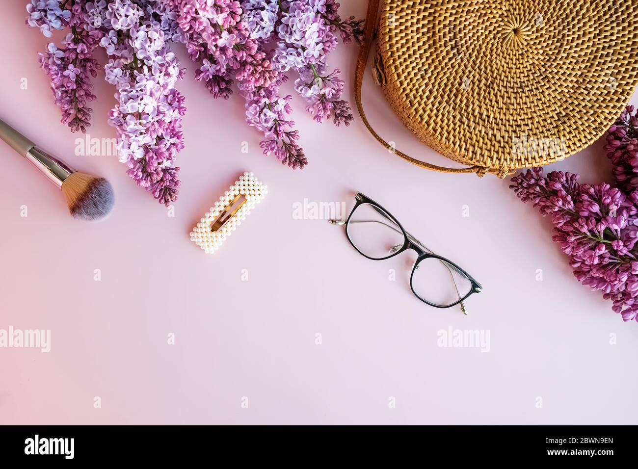 Sacco di paglia e fiori lilla su sfondo rosa con spazio per la copia Foto Stock