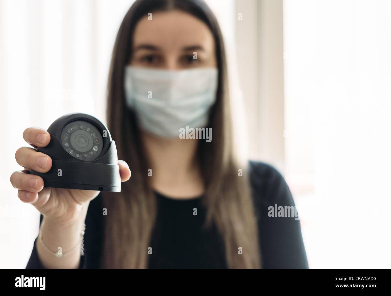 Ragazza con una maschera chirurgica che tiene una macchina fotografica spia  in una mano. Chiuso a chiave in casa. Quarantena. Covid-19 coronavirus  pandemico Foto stock - Alamy