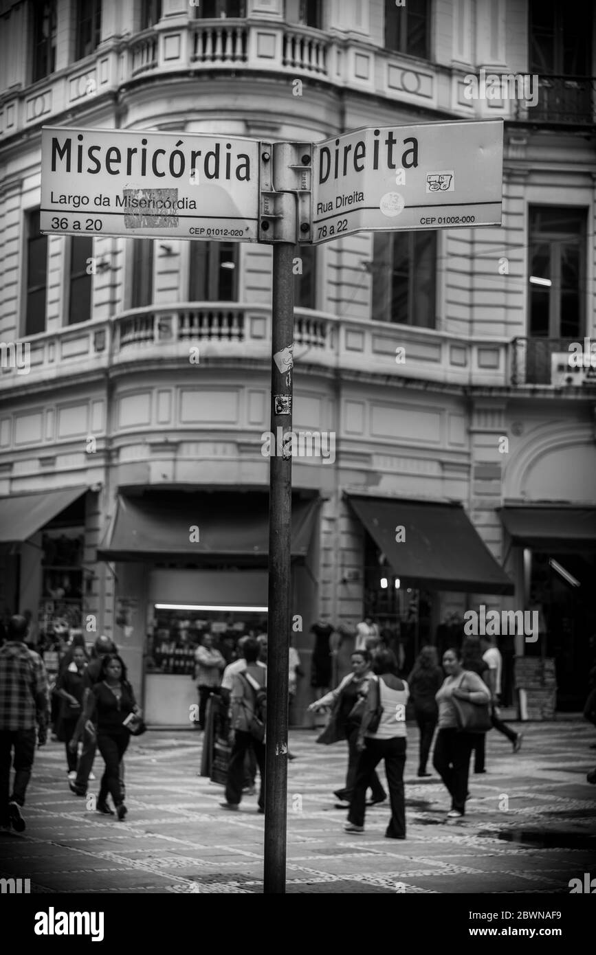Persone casuali che camminano per le strade di San Paolo, con cartelli stradali visibili in primo piano Foto Stock