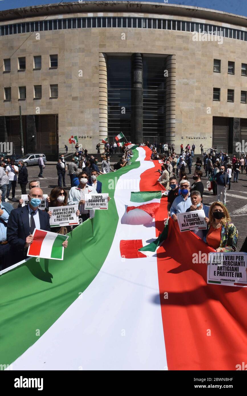 Le persone che indossano una maschera protettiva portano segni di 'time out', 'assistenza reale per rivenditori, profassionals e artigiani' e 'tassa flat e fiducia commerciale' accanto ad un gigantesco banner nei colori della bandiera italiana durante la Lega per Salvini e FDI ( Fratelli d'Italia) I partiti protestano contro i piani di aiuto dell'Unione europea per i paesi più colpiti dal Covid-19 e contro il piano del governo italiano di riavviare l'economia. Foto Stock