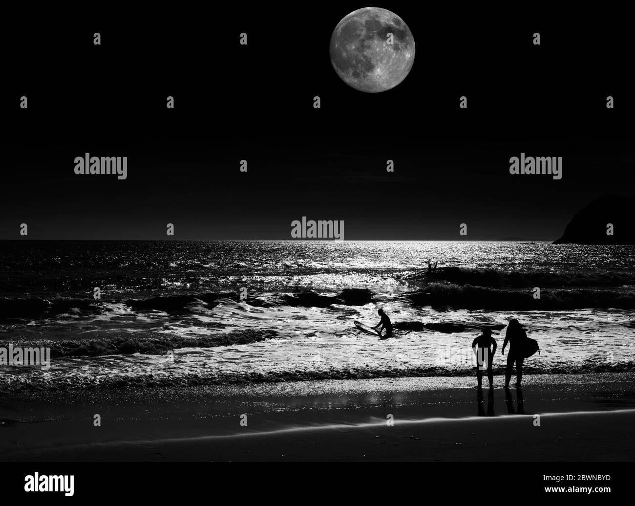 Surfers di notte sulla spiaggia di Dun Cin Tire illuminata da una luna super, vicino a Dingle Town, Dingle Peninsula, County Kerry, Irlanda Foto Stock
