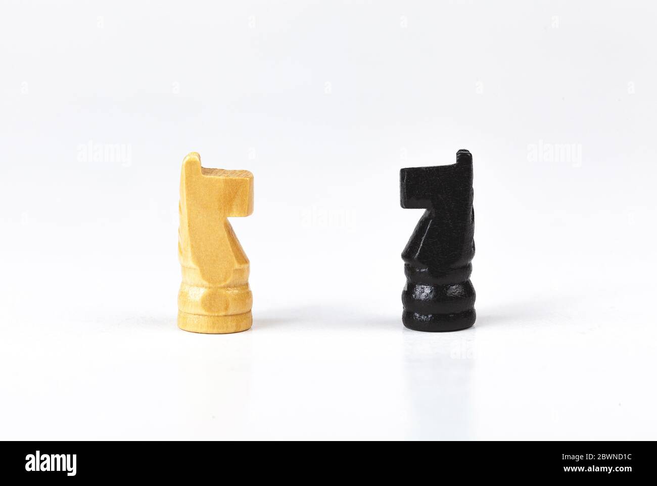 Due semplici cavalieri bianchi e neri, pezzi di scacchi a cavallo opposti, l'uno di fronte all'altro, faccia a faccia, due lati di battaglia, confronto e strategia Foto Stock