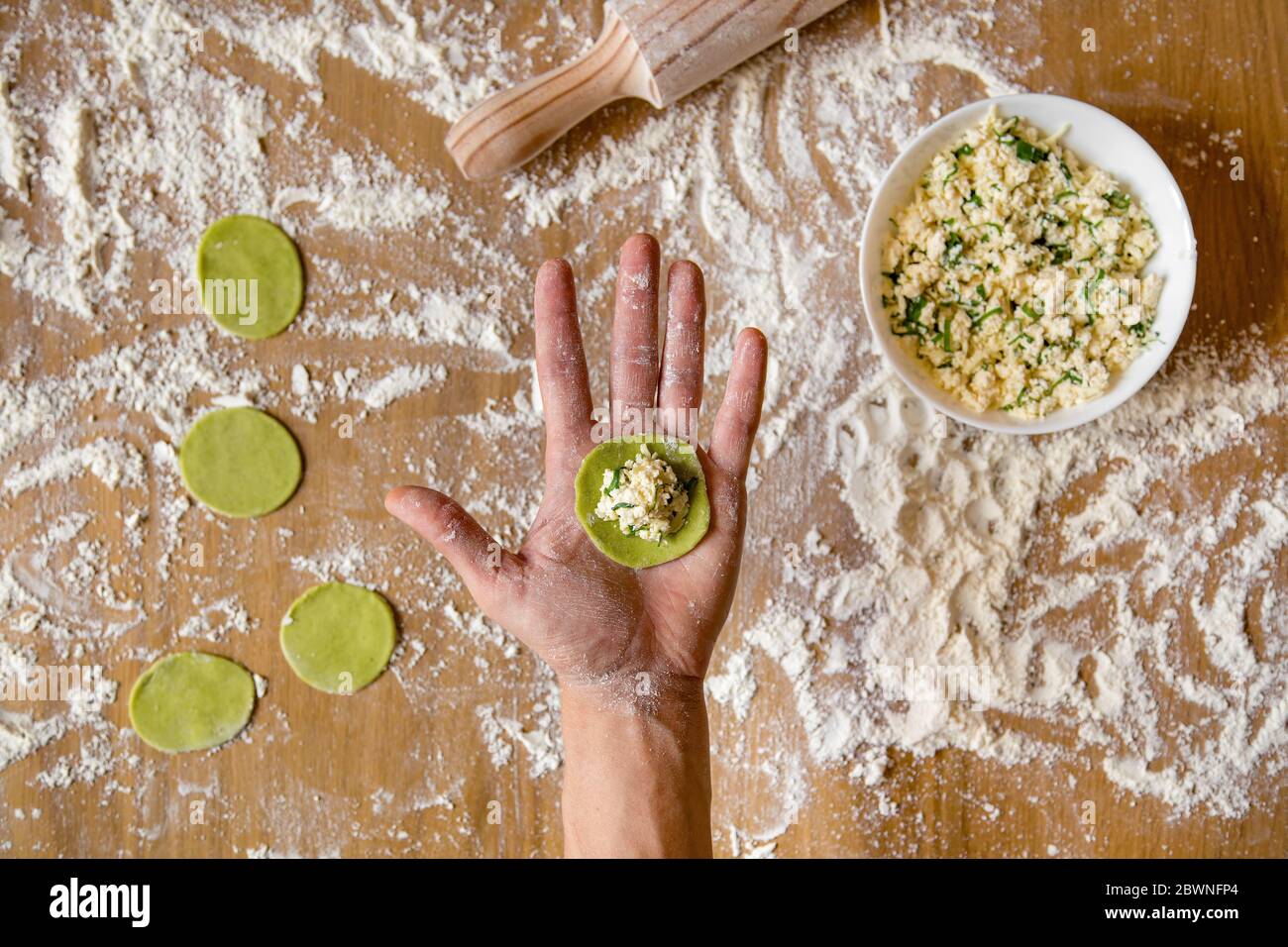 Mani da uomo che tengono un vuoto per gnocchi vegetali. Preparazione di gnocchi di carne sul tavolo di legno. Foto Stock