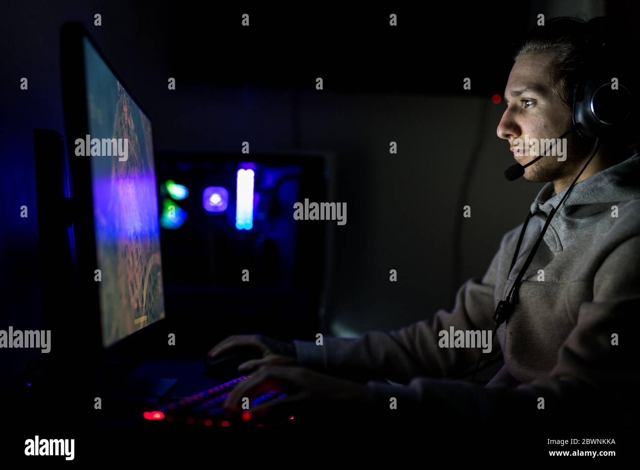 Videogamer o Streamer professionista giocare a Sparatutto in prima persona Video Game online su un PC di gioco personalizzato. Indossa una cuffia e sta giocando su Foto Stock