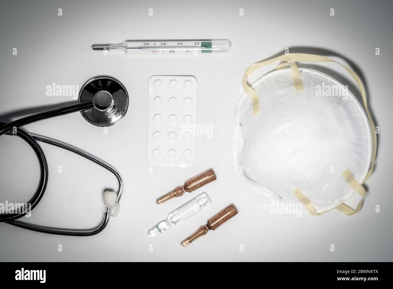 Maschere mediche con elastico, termometro, medicina e stetoscopio, isolate su sfondo bianco. Concetto sanitario e medico. Foto Stock