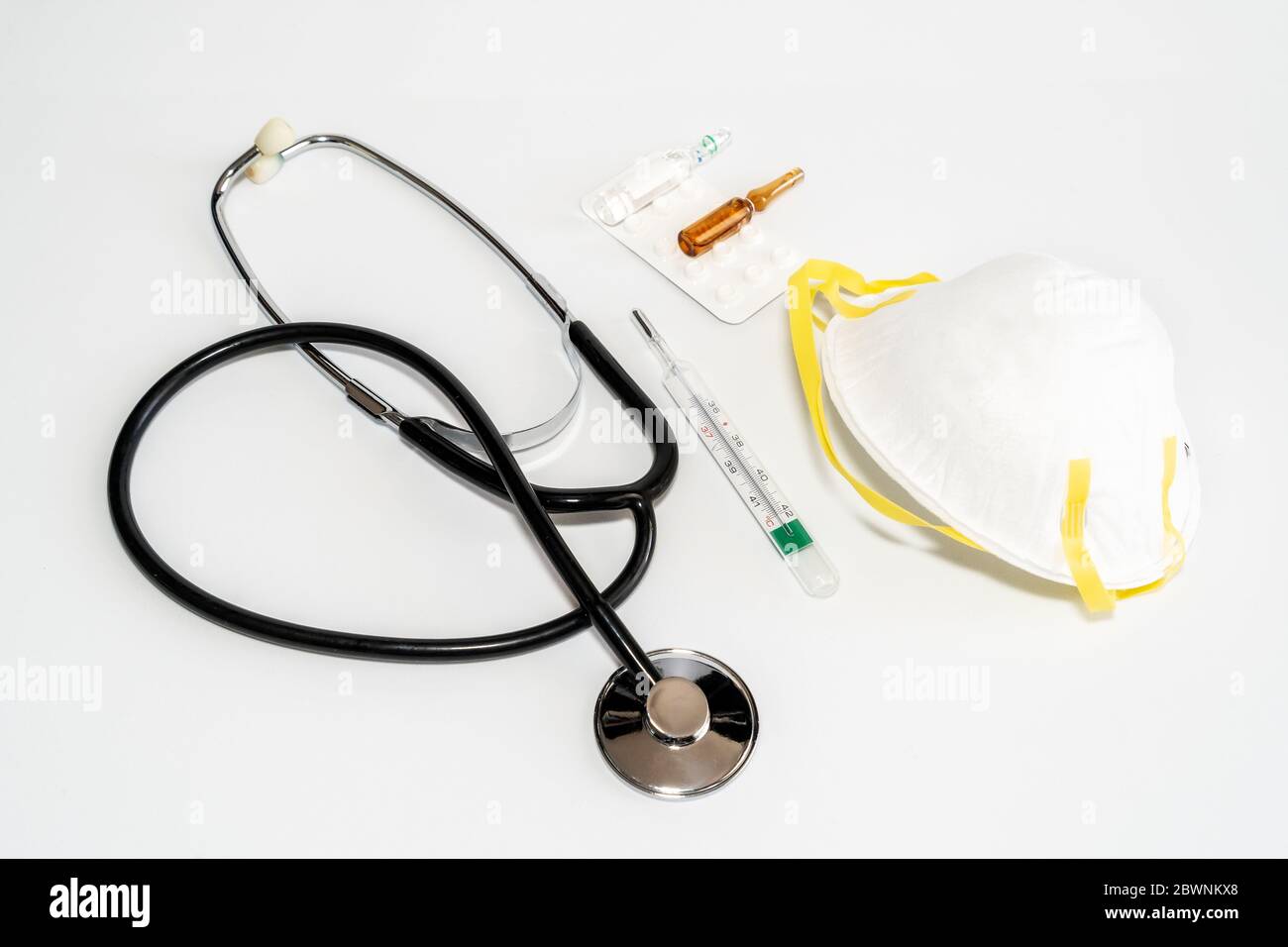 Maschere mediche con elastico, termometro, medicina e stetoscopio, isolate su sfondo bianco. Concetto sanitario e medico. Foto di alta qualità Foto Stock