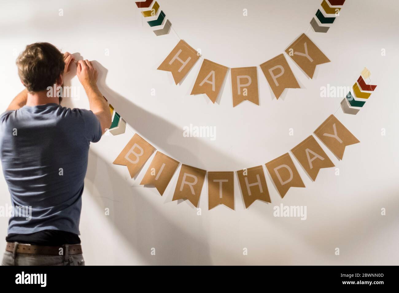 L'uomo appende il cartello di buon compleanno su un muro Foto Stock