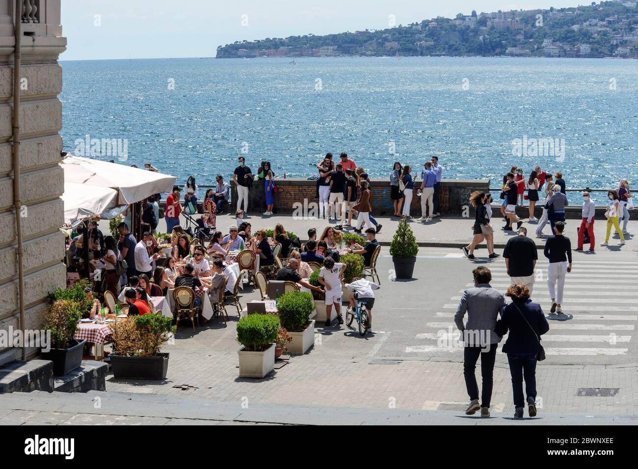 Persone sedute ai tavoli del ristorante sul lungomare di Napoli. Il governo italiano ha fermato un blocco a livello nazionale dovuto alla diffusione della malattia del coronavirus, consentendo la riapertura di tutte le attività e la mobilità dei cittadini. L'Italia, come molti altri paesi del mondo, sta gradualmente allentando le restrizioni di blocco della COVID-19 nel tentativo di riavviare la sua economia e aiutare le persone nelle loro routine quotidiane dopo lo scoppio della pandemia del coronavirus. Foto Stock