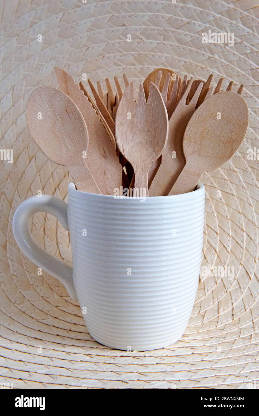 Posate in legno in tazza di ceramica con fondo foglia di palma. Concetto di zero sprechi. Foto Stock