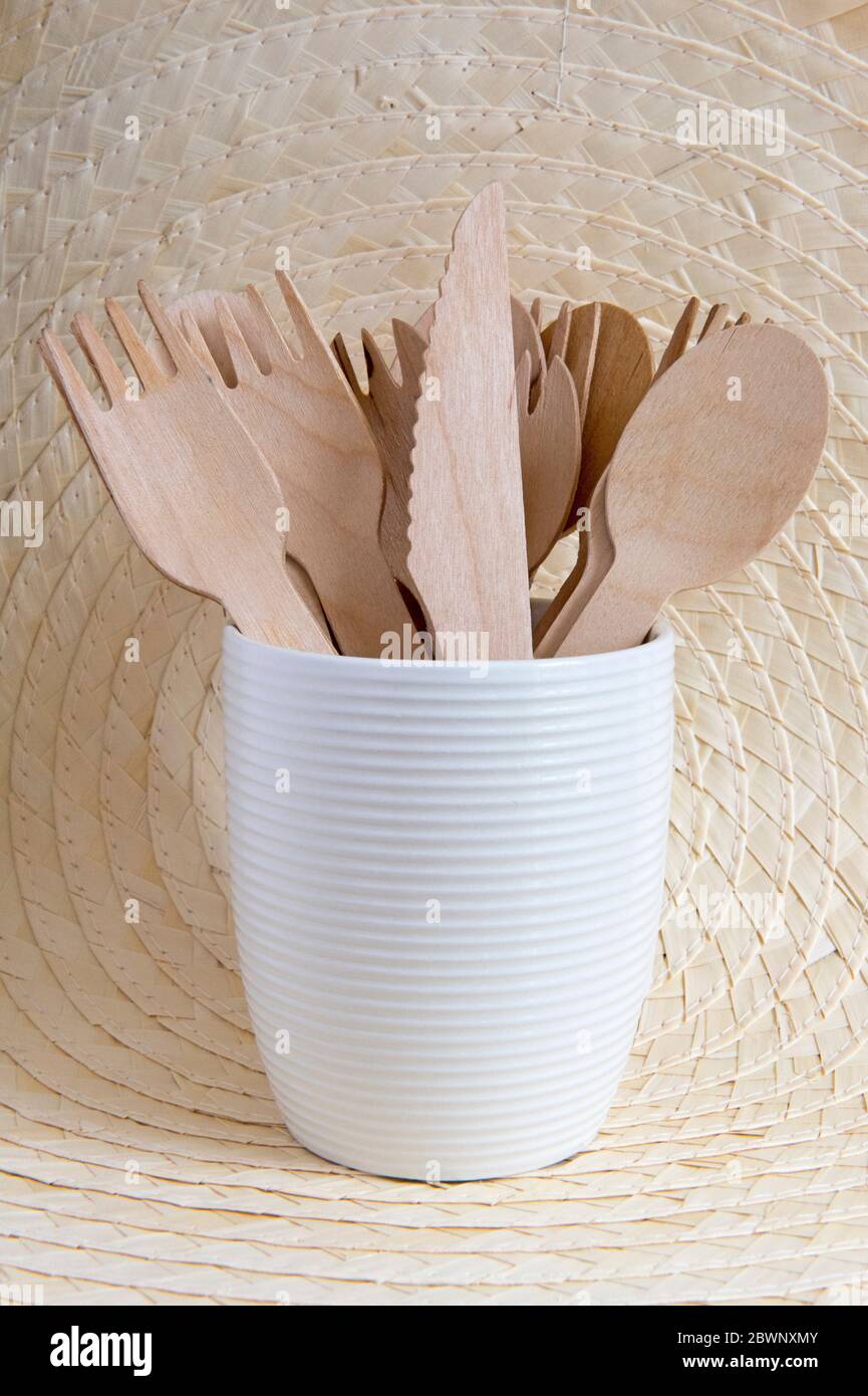 Posate in legno in vaso di ceramica con sfondo a foglia di palma. Concetto di zero sprechi. Foto Stock