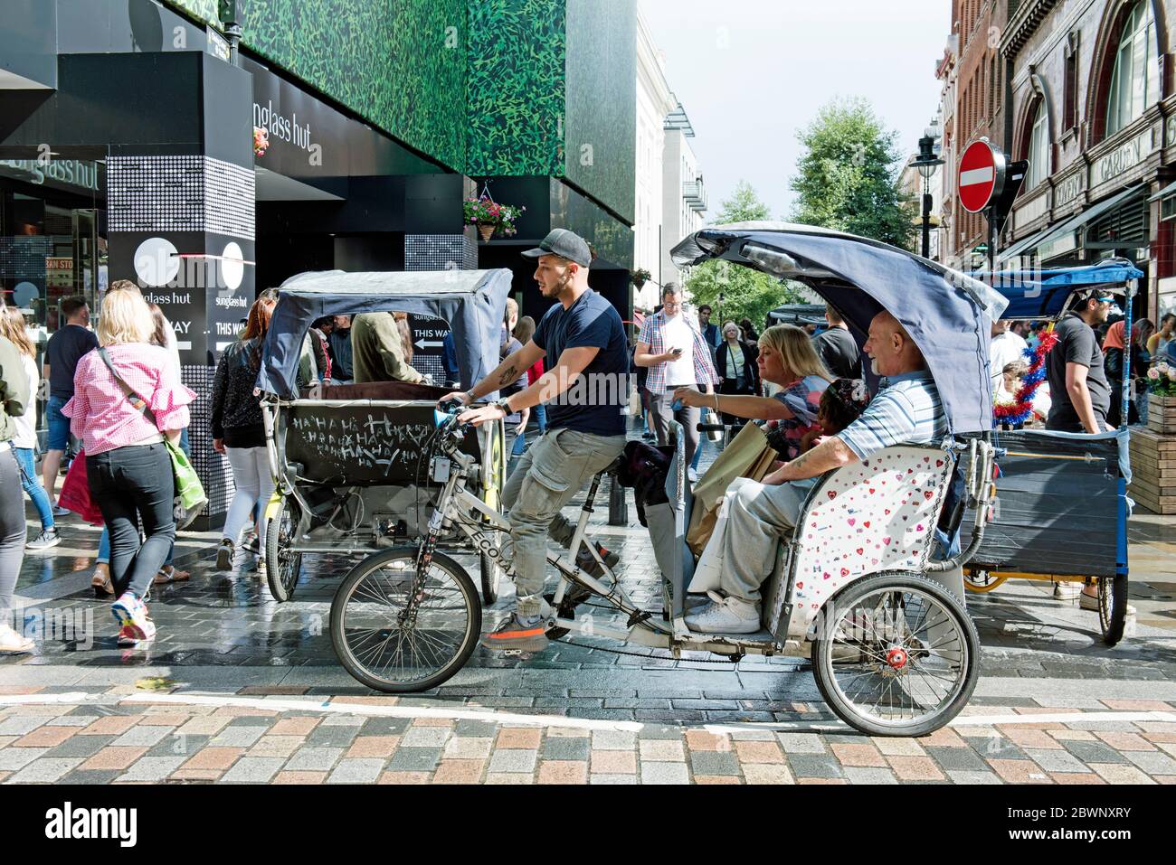 Ecotaxi, pedicab o risciò in bicicletta urbana con cavaliere e passanti Covent Garden, Londra Centrale, Inghilterra Gran Bretagna Foto Stock
